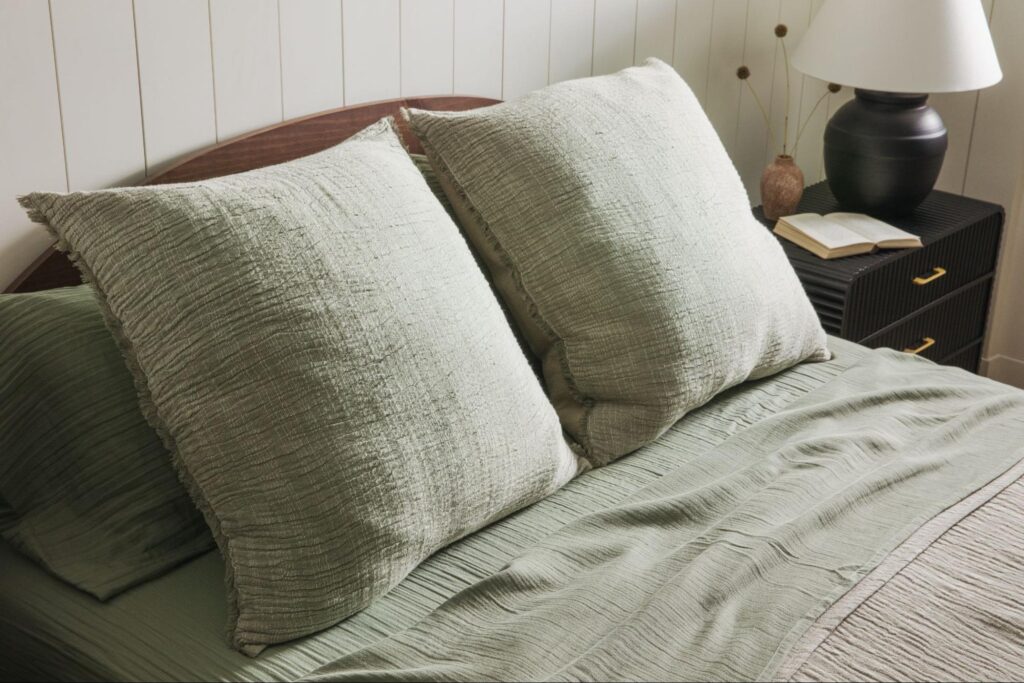 Sage green throw pillows over sage green bedsheets