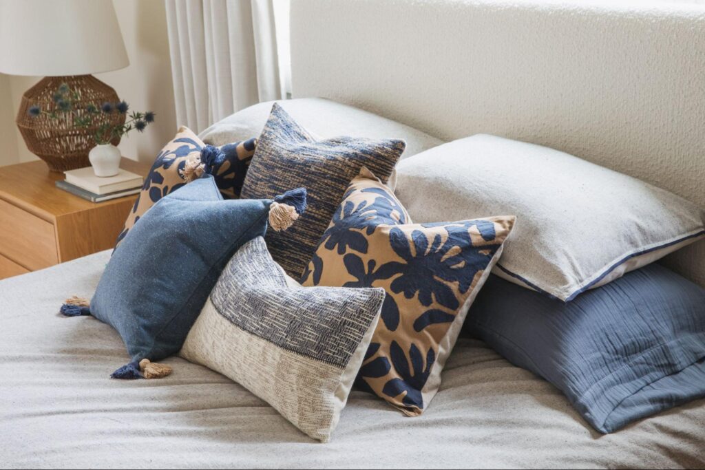 Head of a bed decorated with blue, brown and gray accent pillows
